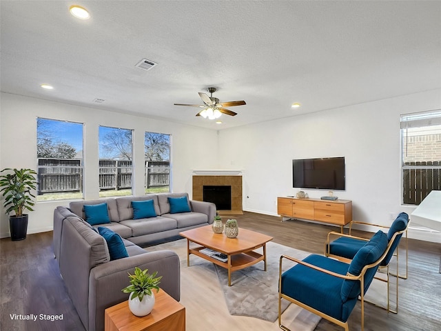 living room featuring visible vents, wood finished floors, a textured ceiling, a fireplace, and recessed lighting