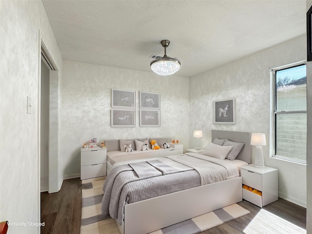 bedroom featuring a textured ceiling, wood finished floors, and baseboards