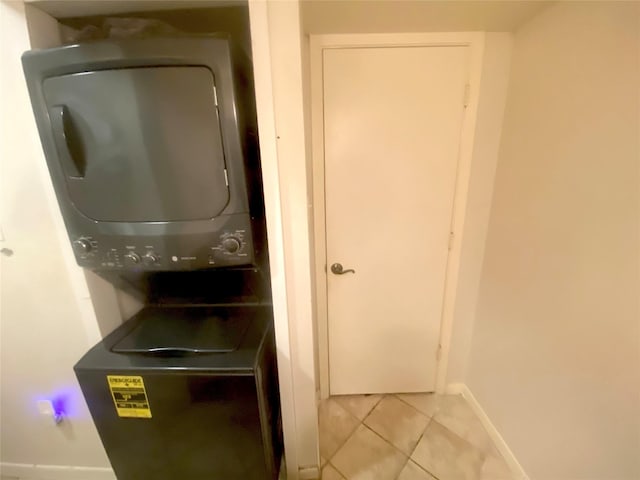 laundry room featuring stacked washer / drying machine and light tile patterned floors