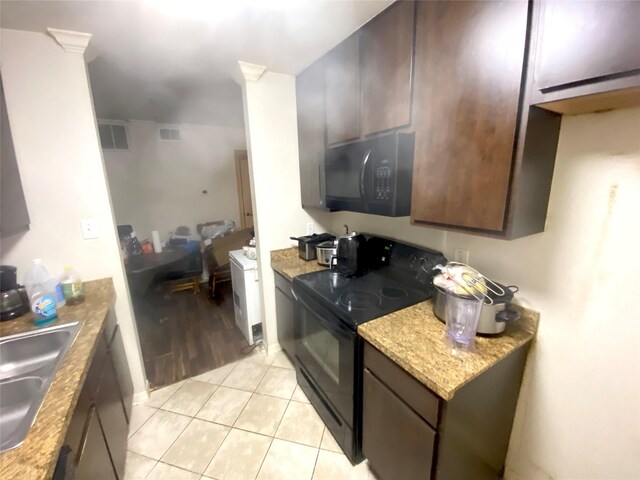 kitchen featuring light tile patterned flooring, black appliances, sink, light stone counters, and dark brown cabinetry