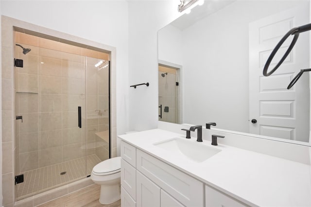 bathroom featuring vanity, an enclosed shower, hardwood / wood-style floors, and toilet