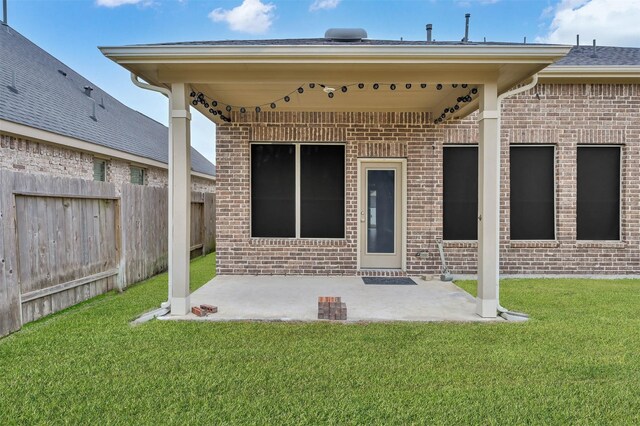 view of exterior entry with a patio and a lawn