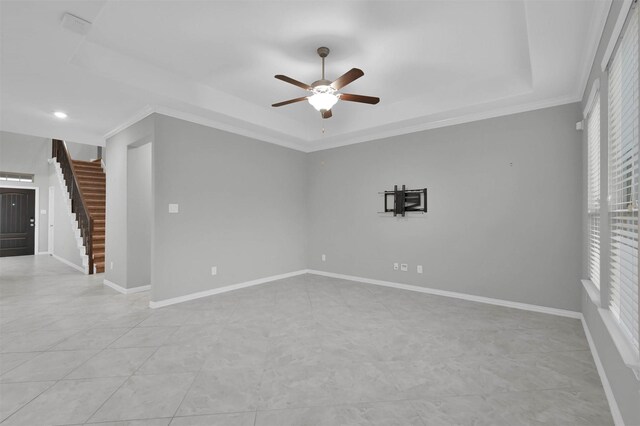 spare room with crown molding, ceiling fan, a raised ceiling, and light tile patterned flooring