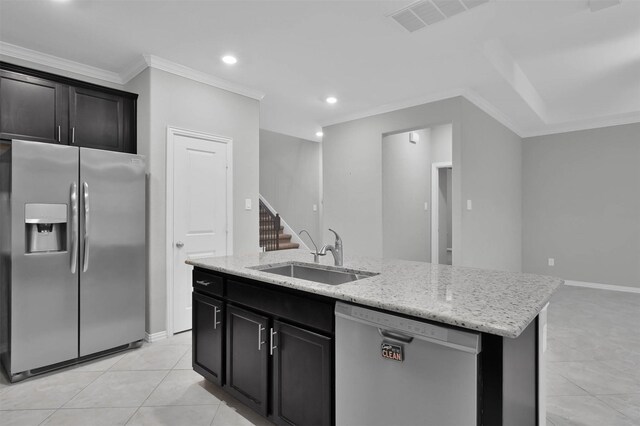 kitchen with sink, crown molding, light tile patterned floors, appliances with stainless steel finishes, and a center island with sink