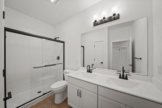 bathroom with vanity, hardwood / wood-style flooring, a shower with shower door, and toilet