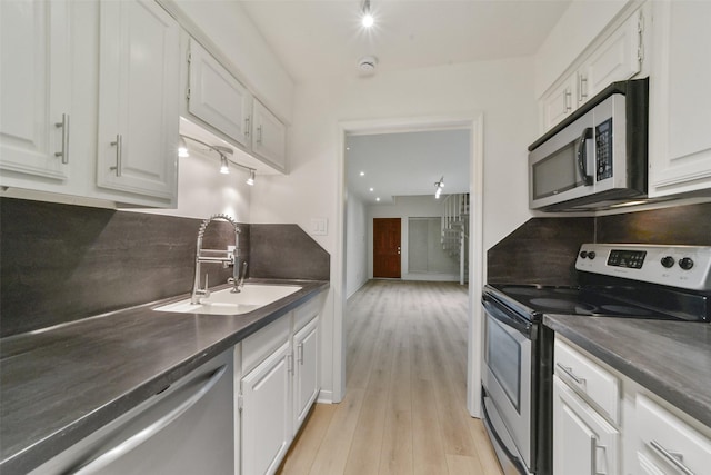 kitchen featuring sink, appliances with stainless steel finishes, white cabinets, light hardwood / wood-style floors, and backsplash