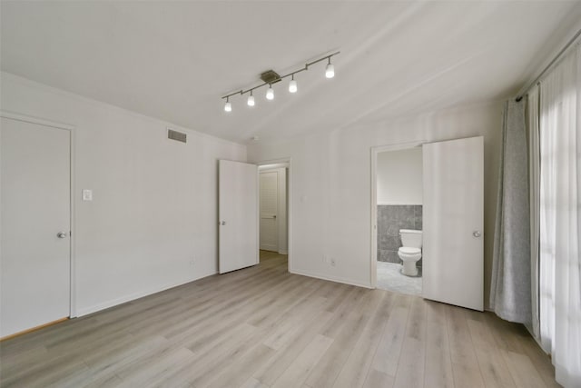 unfurnished bedroom with ensuite bathroom and light wood-type flooring