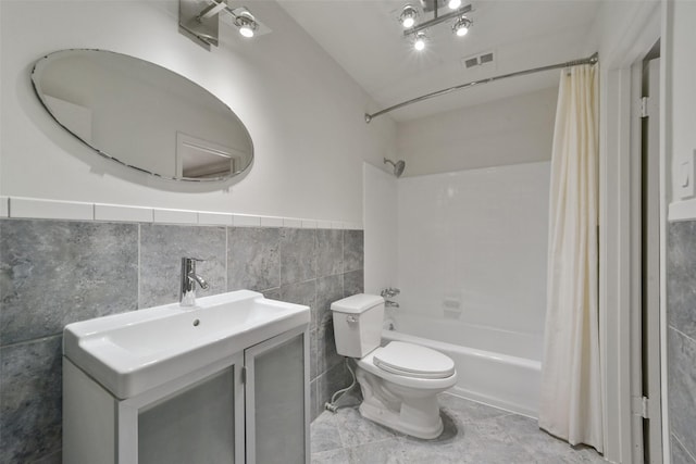 full bathroom featuring shower / bath combination with curtain, vanity, toilet, and tile walls