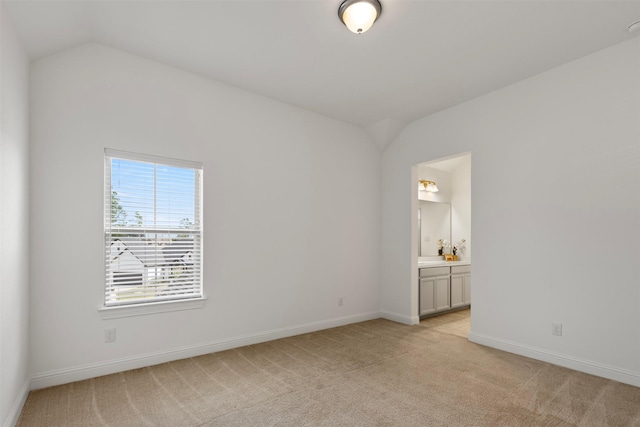 empty room featuring vaulted ceiling and light carpet