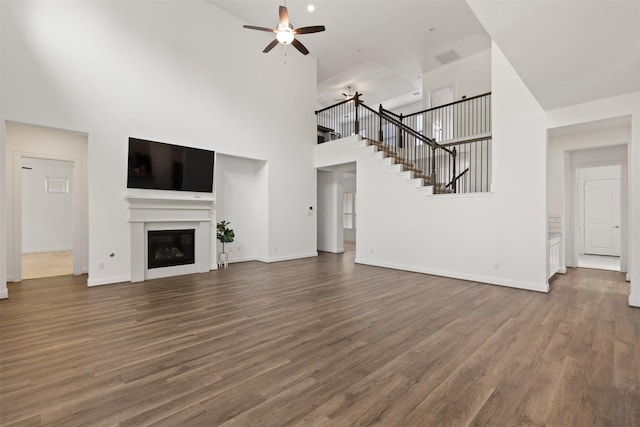 unfurnished living room with dark hardwood / wood-style floors, ceiling fan, and a high ceiling