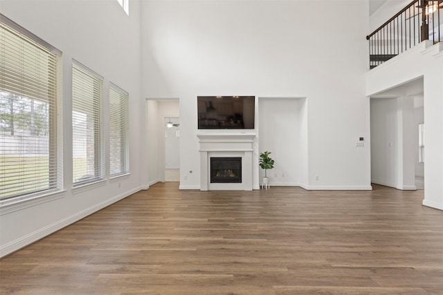 unfurnished living room with a towering ceiling and hardwood / wood-style floors