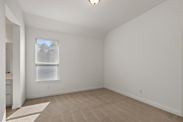 carpeted spare room with vaulted ceiling