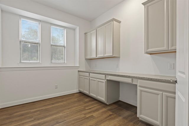 unfurnished office featuring dark wood-type flooring and built in desk