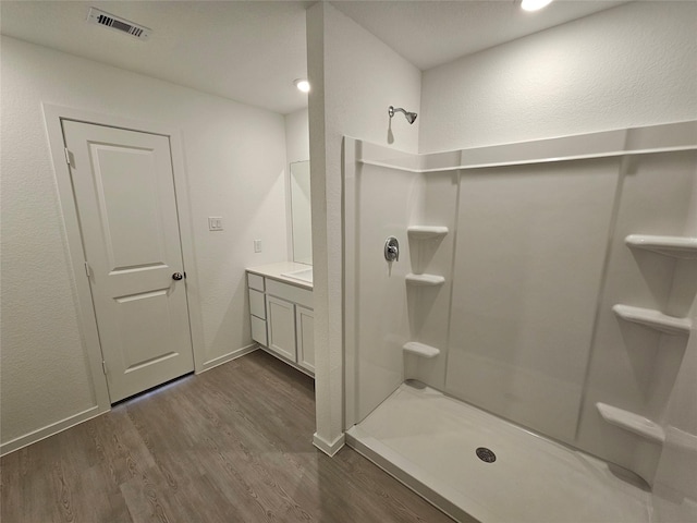 bathroom featuring walk in shower, vanity, and hardwood / wood-style floors