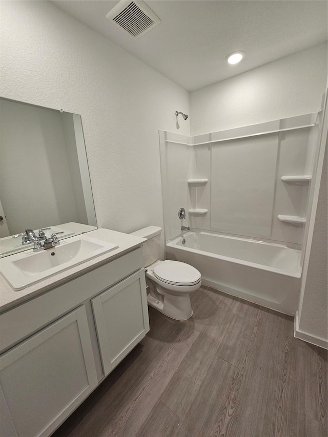 full bathroom featuring washtub / shower combination, wood-type flooring, toilet, and vanity