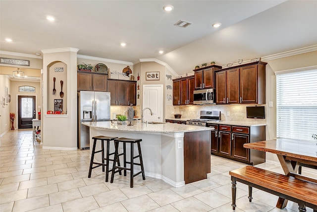 kitchen featuring sink, light tile patterned floors, appliances with stainless steel finishes, a kitchen island with sink, and light stone counters