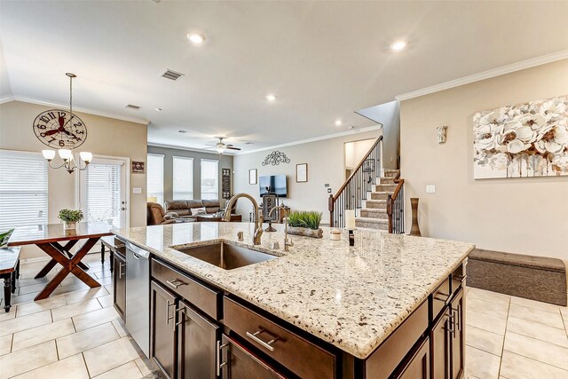 kitchen with sink, light stone counters, hanging light fixtures, dishwasher, and a kitchen island with sink