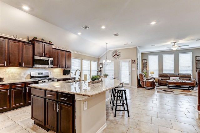 kitchen featuring light tile patterned floors, a kitchen island with sink, hanging light fixtures, stainless steel appliances, and decorative backsplash