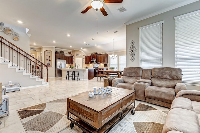 living room featuring light tile patterned floors, ceiling fan with notable chandelier, and ornamental molding