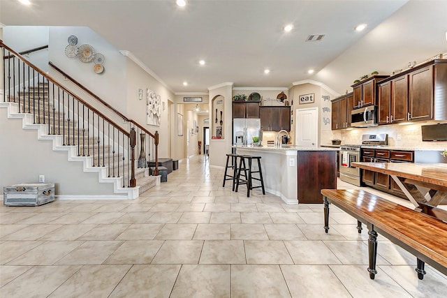 kitchen with light tile patterned floors, a breakfast bar, stainless steel appliances, tasteful backsplash, and an island with sink