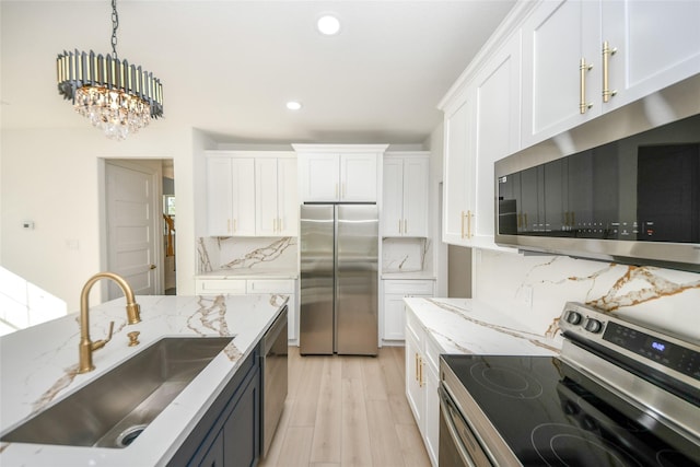 kitchen featuring sink, stainless steel appliances, hanging light fixtures, and white cabinets