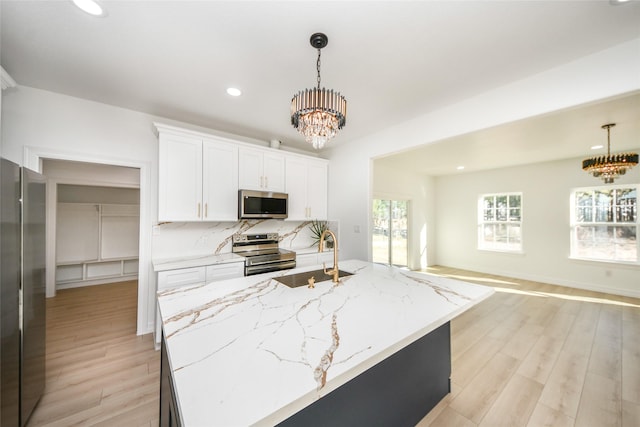 kitchen with stainless steel appliances, a chandelier, sink, and white cabinets