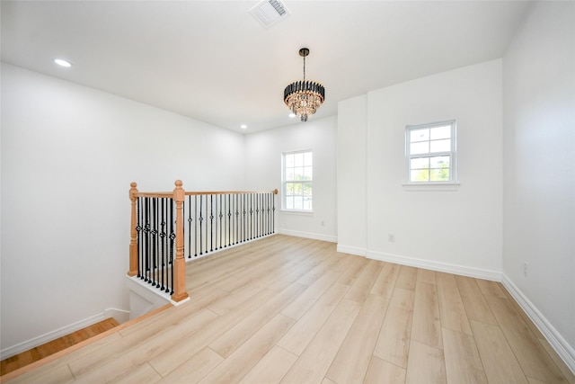 unfurnished room featuring an inviting chandelier and light hardwood / wood-style floors