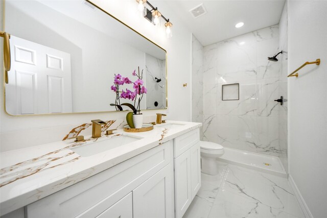 bathroom featuring a tile shower, vanity, and toilet