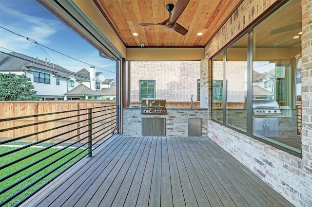 wooden terrace featuring an outdoor kitchen, a grill, sink, and ceiling fan