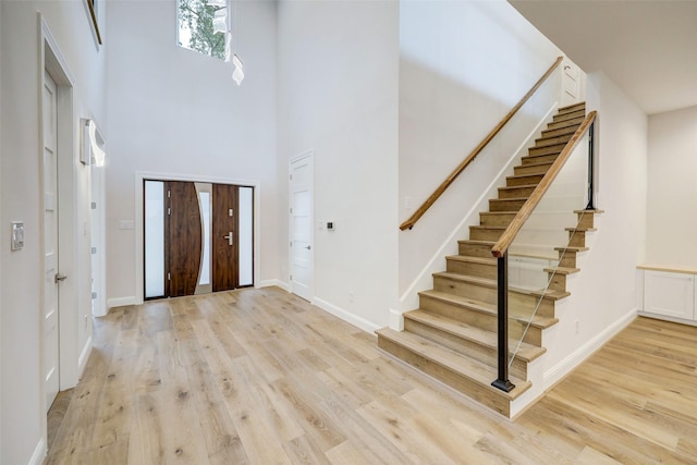 foyer entrance featuring a towering ceiling and light hardwood / wood-style floors