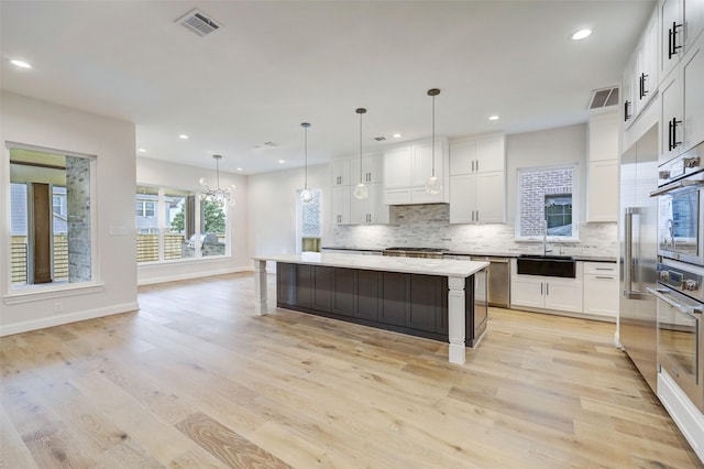 kitchen with hanging light fixtures, a center island, white cabinets, and oven