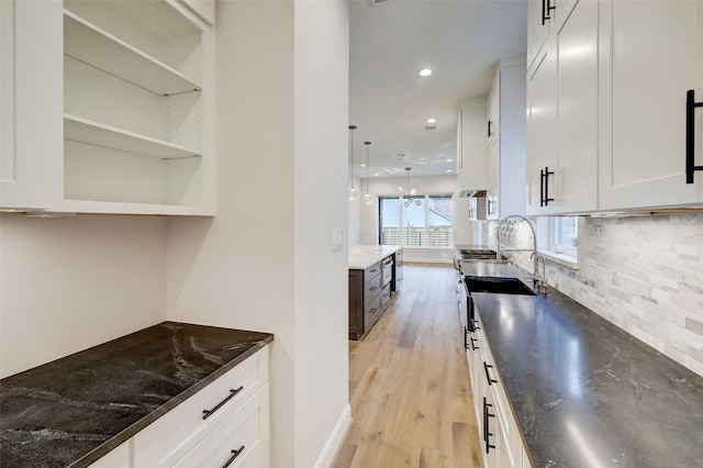 kitchen with white cabinetry, dark stone countertops, and backsplash