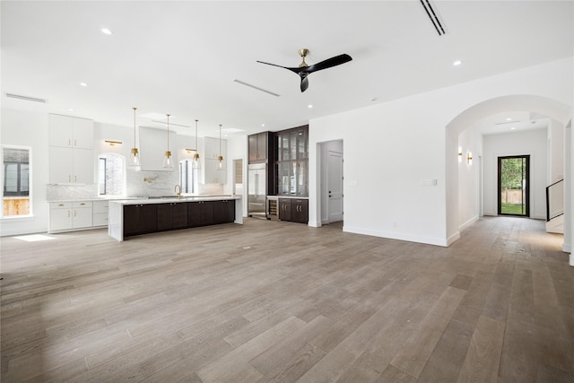 unfurnished living room with ceiling fan, sink, and light hardwood / wood-style floors