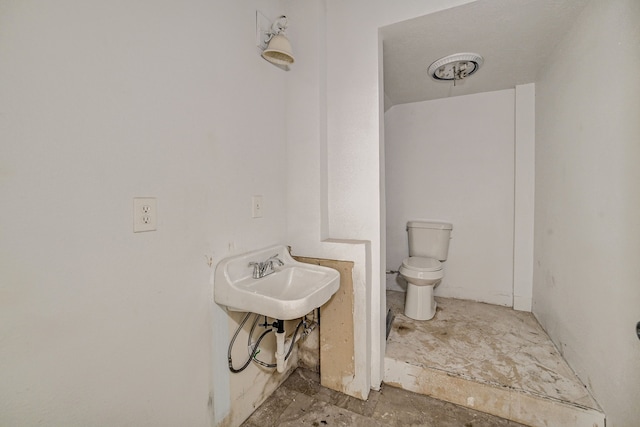 bathroom with toilet, sink, and concrete floors