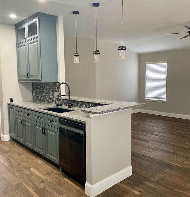 kitchen with wood-type flooring, light stone countertops, sink, and pendant lighting