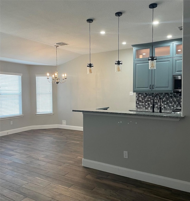 kitchen featuring dark wood-type flooring, sink, tasteful backsplash, a textured ceiling, and pendant lighting