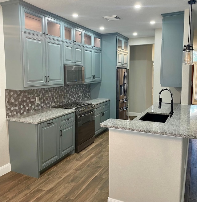 kitchen featuring stainless steel appliances, sink, dark wood-type flooring, and kitchen peninsula