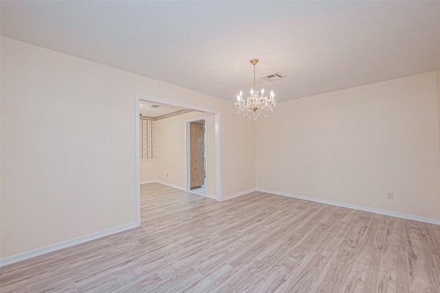 empty room with light hardwood / wood-style flooring and a chandelier