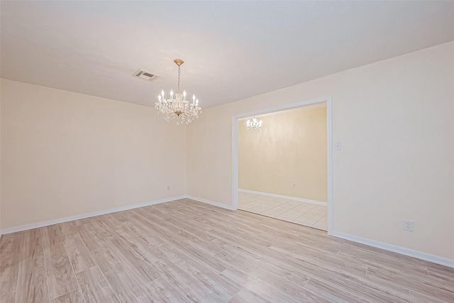 empty room with a notable chandelier and light hardwood / wood-style flooring