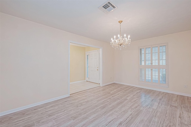 empty room with a notable chandelier and light hardwood / wood-style floors