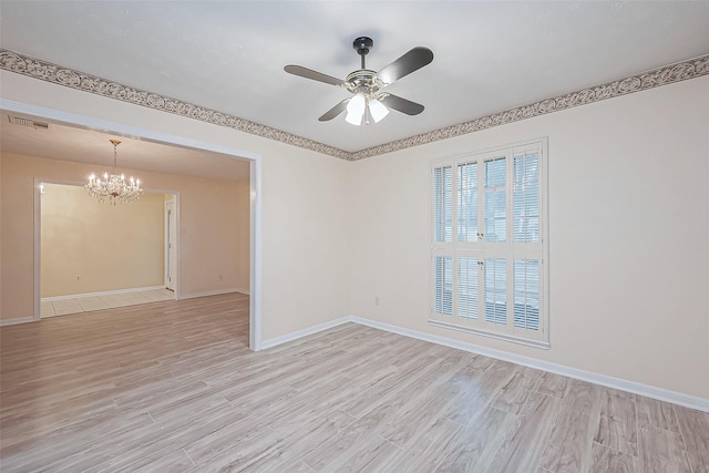 spare room with ceiling fan with notable chandelier and light hardwood / wood-style floors