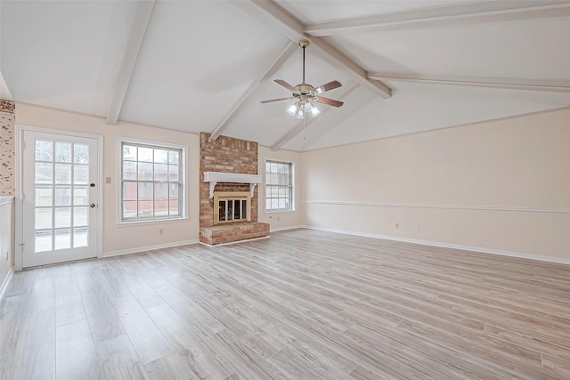 unfurnished living room with lofted ceiling with beams, a brick fireplace, ceiling fan, and light hardwood / wood-style flooring