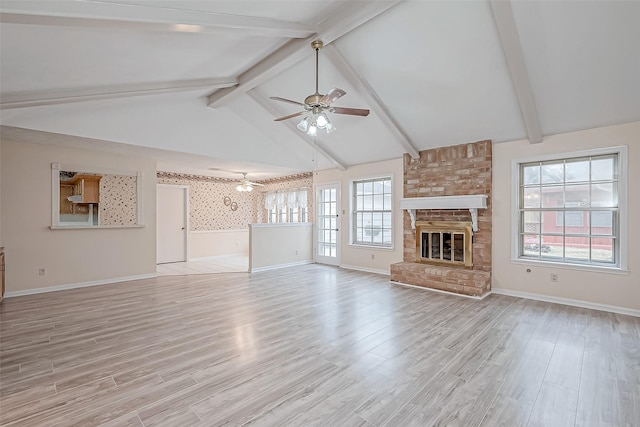 unfurnished living room with ceiling fan, a fireplace, lofted ceiling with beams, and light wood-type flooring