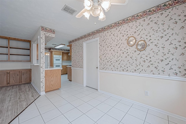 kitchen featuring light tile patterned flooring, ceiling fan, and white double oven