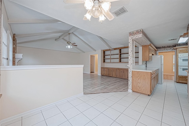 kitchen with vaulted ceiling with beams, white double oven, fridge, light tile patterned floors, and ceiling fan