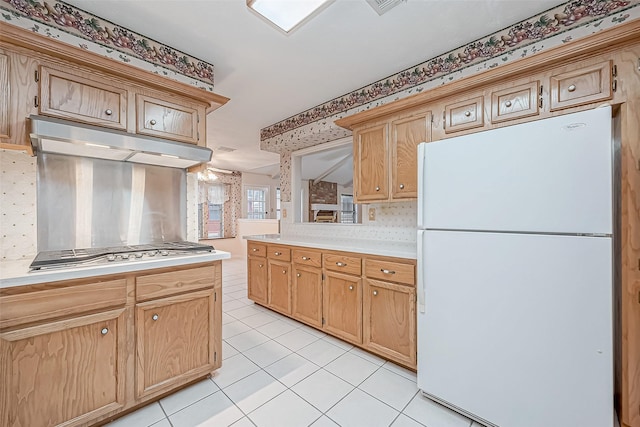 kitchen with decorative backsplash, light tile patterned flooring, stainless steel gas cooktop, and white refrigerator