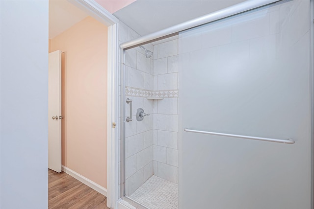 bathroom with hardwood / wood-style flooring and a shower with door