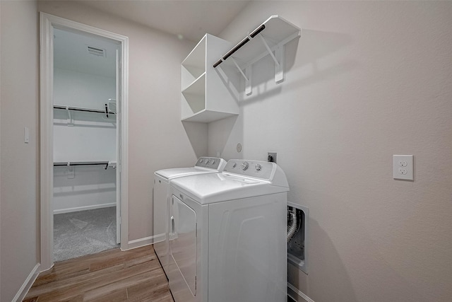 laundry room featuring laundry area, wood finished floors, washing machine and dryer, and baseboards