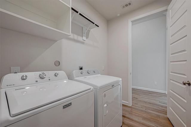 laundry area with washing machine and dryer and light hardwood / wood-style floors