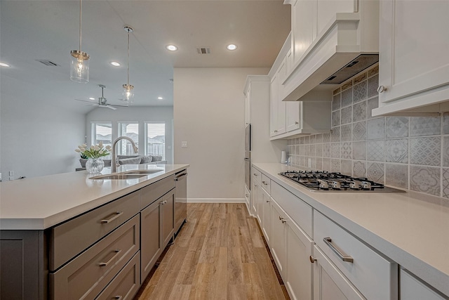 kitchen featuring visible vents, custom range hood, stainless steel appliances, light countertops, and a sink